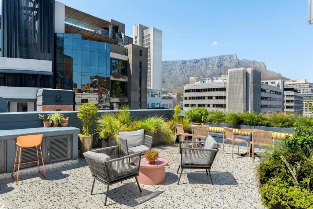a patio with chairs and tables on top of a building at Hotel Apt, Wifi, Roof Deck, Central CBD, 247 Power in Cape Town
