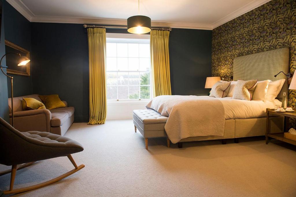 a bedroom with a bed and a chair and a window at Purchases Restaurant & Accommodation in Chichester