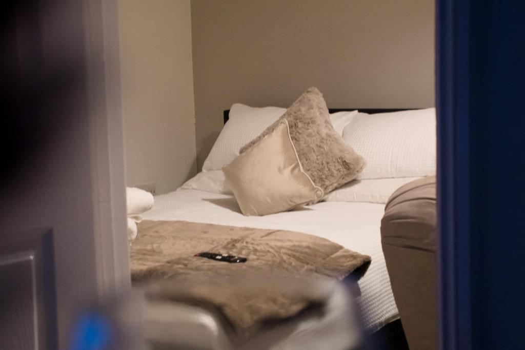 uma cama com lençóis brancos e almofadas num quarto em 1 bedroom apartment - The Opal em Cheltenham