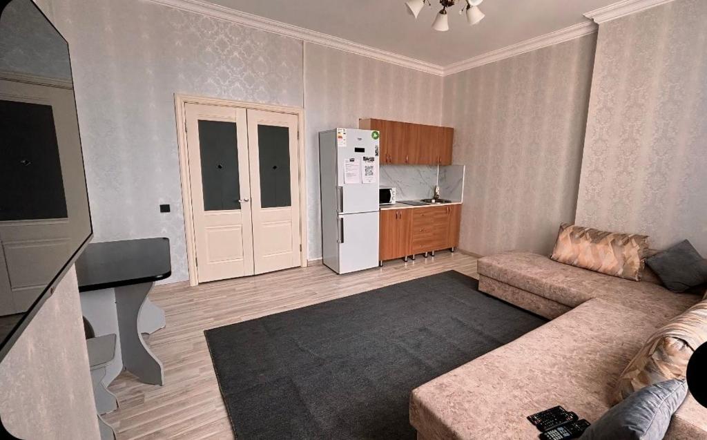uma sala de estar com um sofá e um frigorífico branco em Двухкомнатная квартира на набережной em Astana
