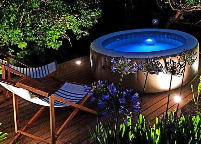 a deck with a hot tub and a chair and flowers at Casa d'Avó Maria in Mira