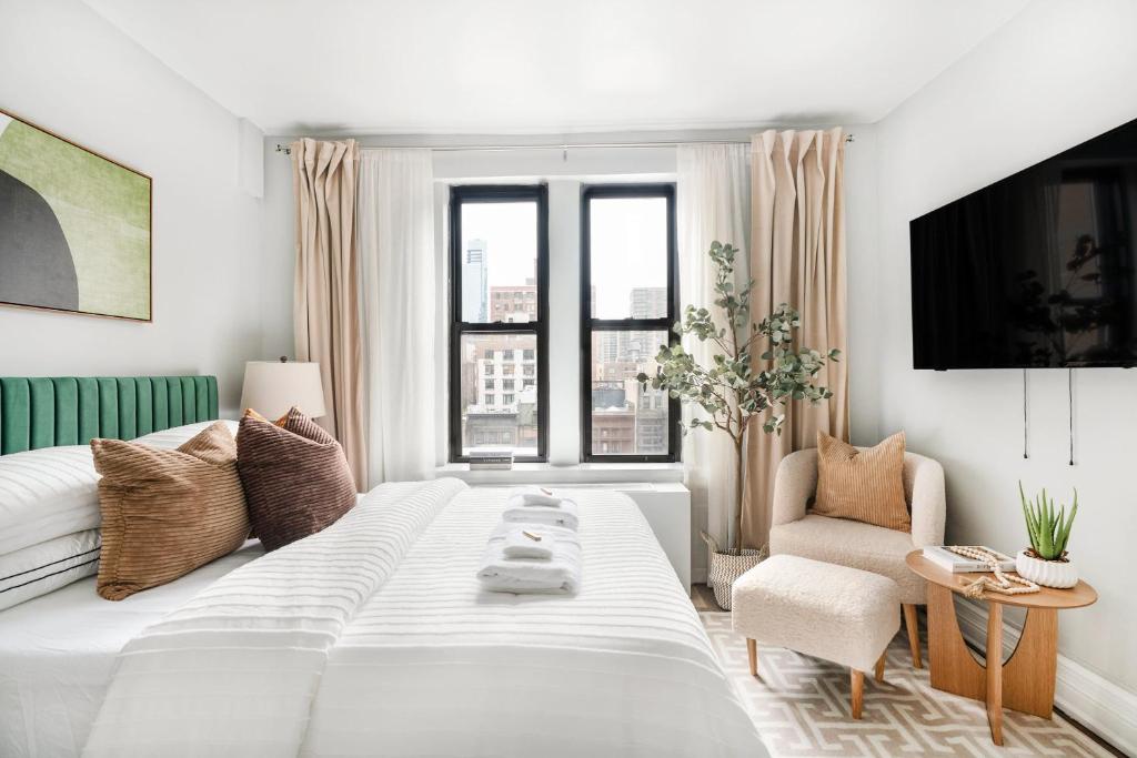 a white bedroom with a large bed and a chair at 73-919 New Studio UWS Doorman Gym in New York