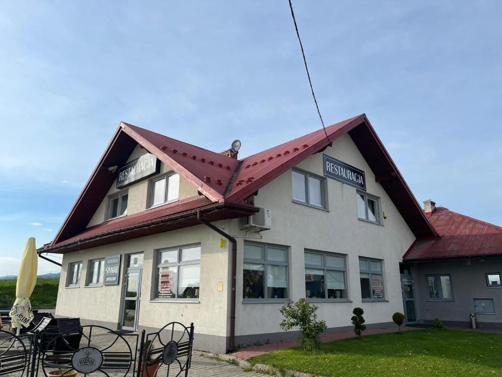 a white building with a red roof with a restaurant at Zajazd Sinmar in Maniowy
