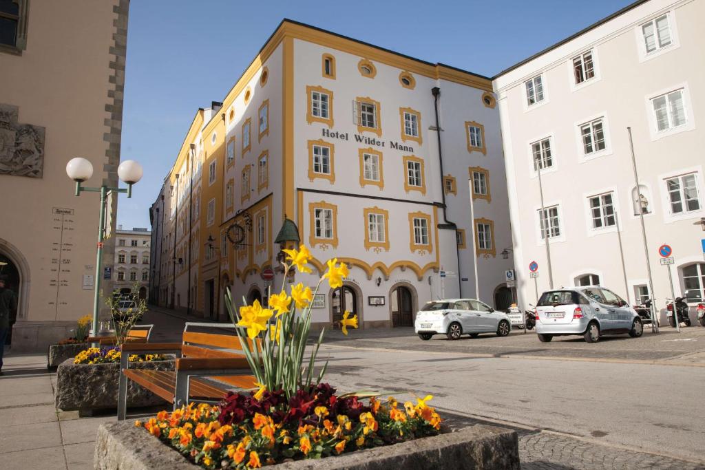 um edifício com um banco e flores na rua em Hotel Wilder Mann em Passau