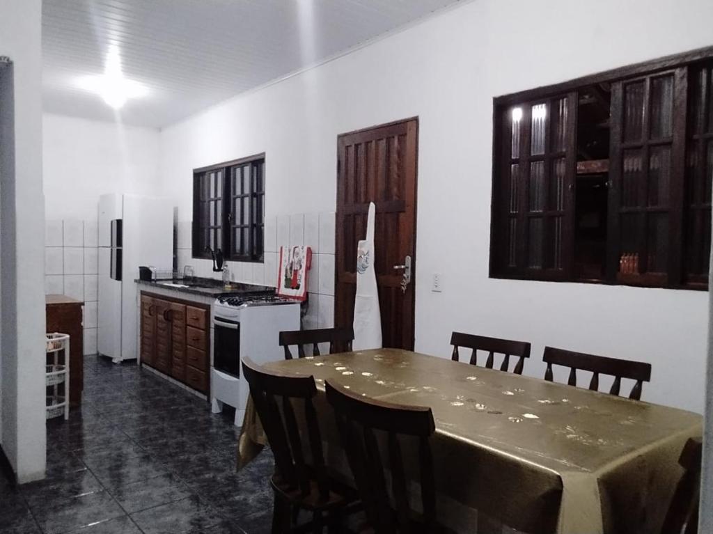 a kitchen with a table with chairs and a stove at Acomodações Casa 2 in Cananéia