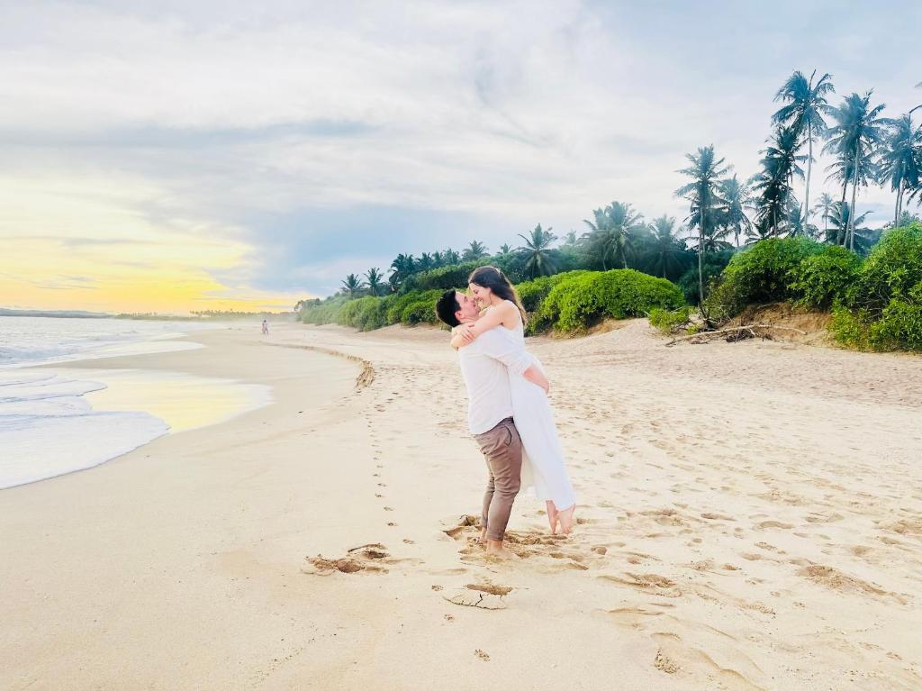 a man carrying a woman on a beach at Shine Wave Turtle Beach in Tangalle