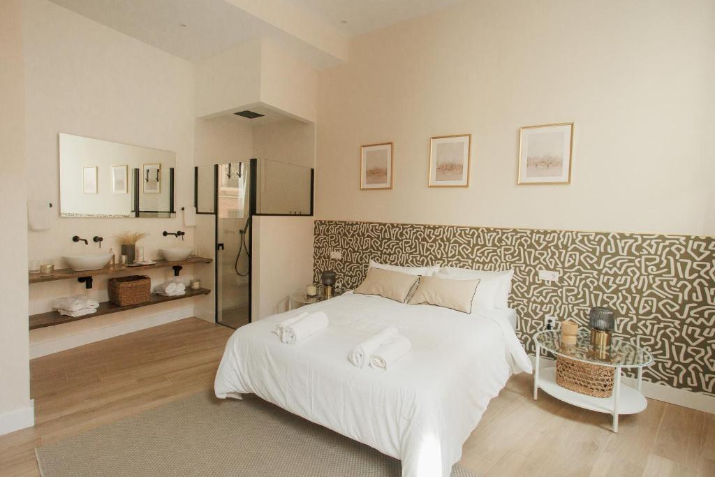 een slaapkamer met een wit bed en een badkamer bij Apartamentos Cervantes in Badajoz