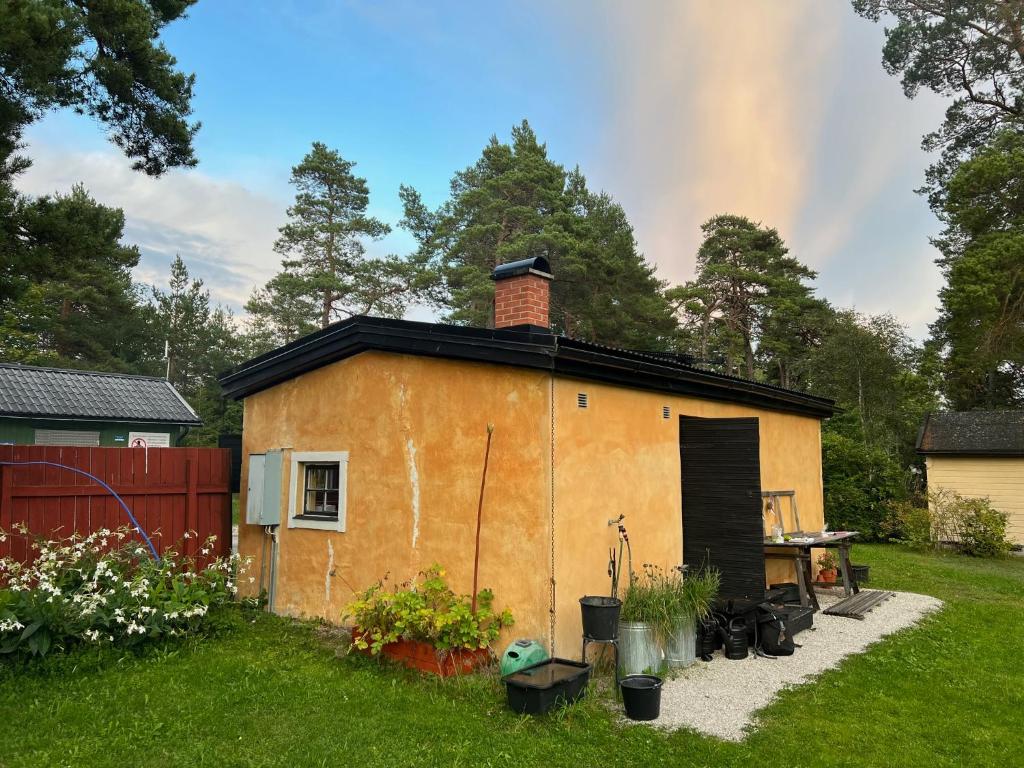 een klein huis met een stenen schoorsteen bovenop bij Mysig stuga i Rute med stor trädgård in Lärbro