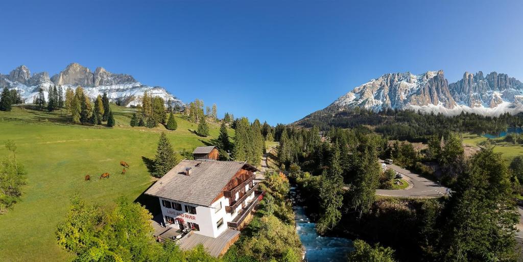 an aerial view of a house in the mountains at Carezza LAKE & RIVER Hotel in Carezza al Lago