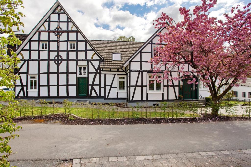 una vecchia casa bianca e nera con un albero di Gut Vasbach Ferienwohnungen a Kirchhundem