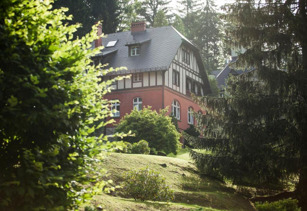 a large red brick house on a hill with trees at Villa Titina in Miedzygorze