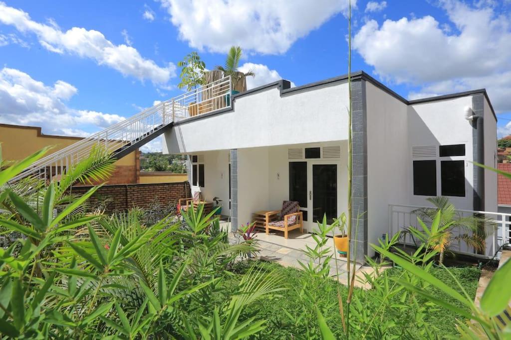 a white house with a staircase on it at Cozy Oasis Large Apt in Center of Kigali Rwanda in Kigali