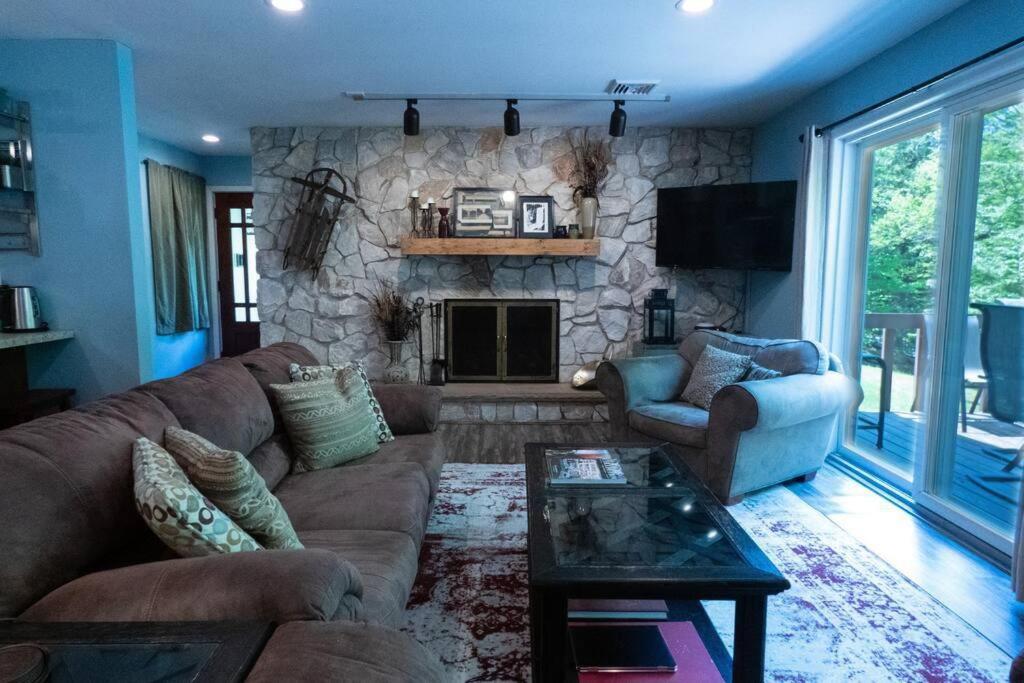 uma sala de estar com um sofá e uma lareira de pedra em Spacious Catskills Home with Covered Hot Tub em Monticello