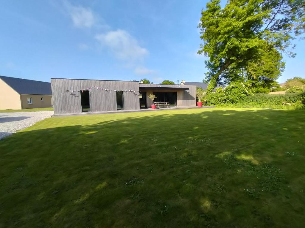 une maison sur une cour herbeuse avec un bâtiment dans l'établissement Maison à louer 80 em anniversaire du débarquement, à Sainte-Marie-du-Mont