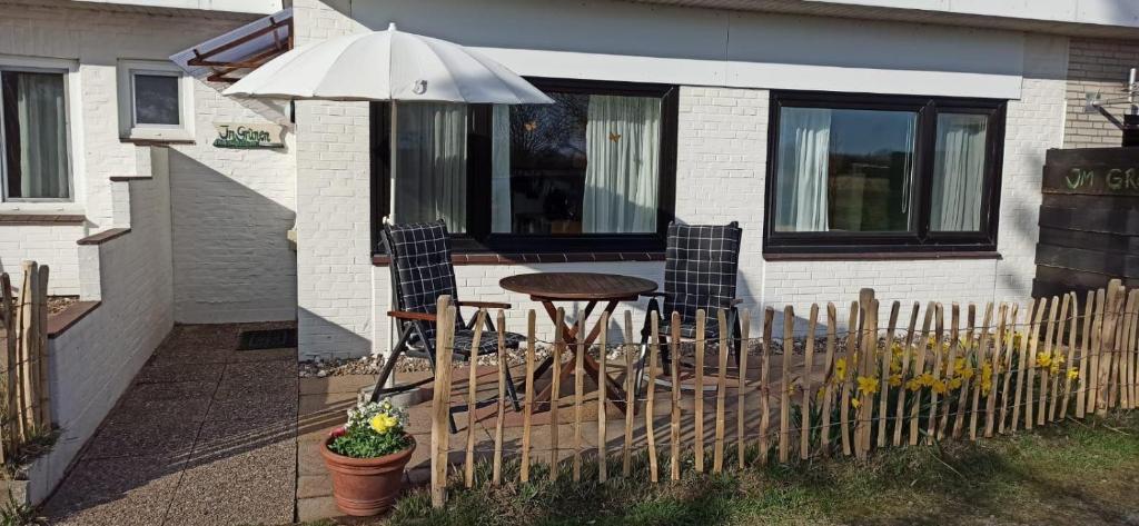 a patio with a table and chairs and an umbrella at Landhaus-Sutje-Im-Gruenen in St. Peter-Ording
