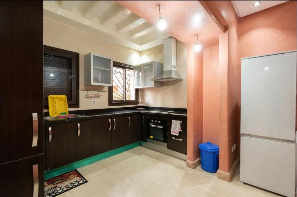 cocina con armarios marrones y nevera blanca en Maison 3 chambres en Marrakech