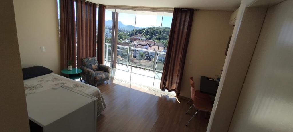 a room with a large window with a view of a house at Pousada Floresta in Joinville