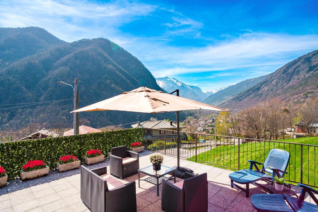 um pátio com uma mesa, cadeiras e um guarda-sol em Case vacanze in graziosa borgata alpina em Villaretto