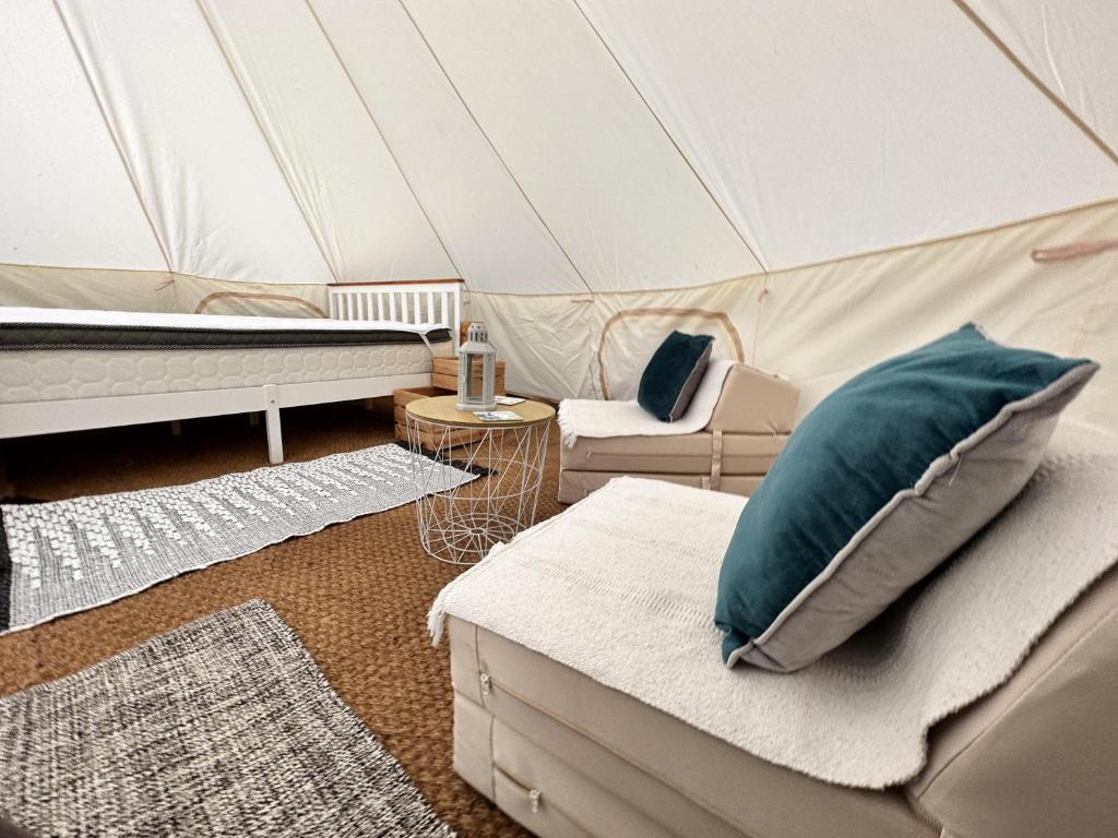 Una habitación con una cama y un sofá en una tienda de campaña en Spacious bell Tent at Herigerbi Park Lincolnshire, en Grantham