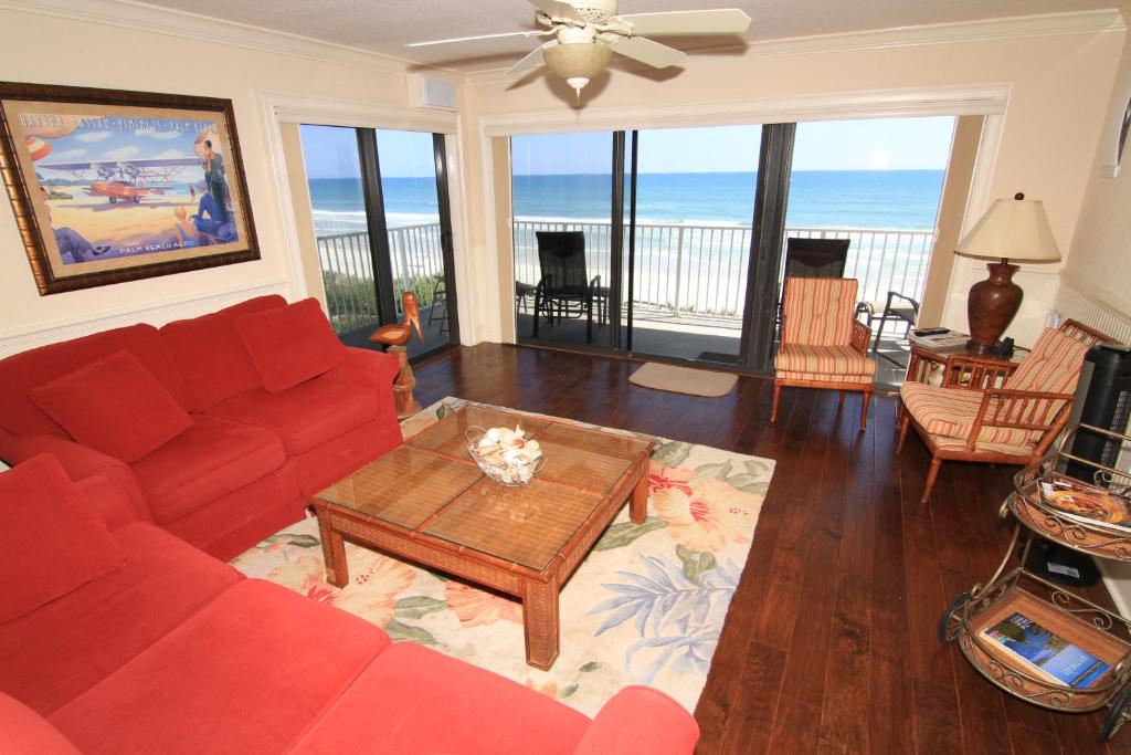 een woonkamer met een rode bank en een tafel bij Oceanfront corner views with wrap around balcony and complex pool in New Smyrna Beach
