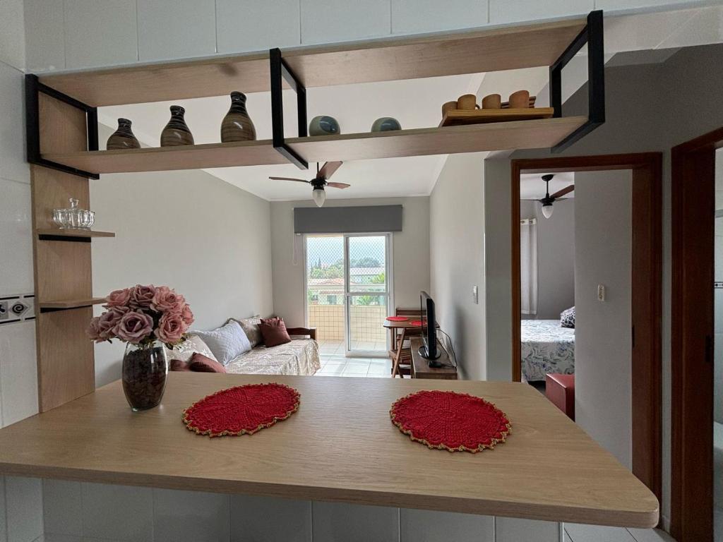 a kitchen with a table with red flowers on it at Apto dos Cardeais in Praia Grande