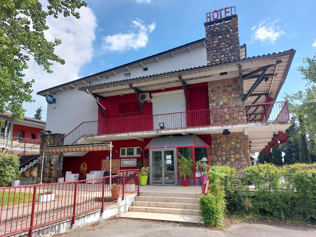 - un bâtiment rouge et blanc avec une terrasse couverte et des escaliers dans l'établissement Logis Hotels - Hôtel Le Relais des Garrigues, à Grisolles