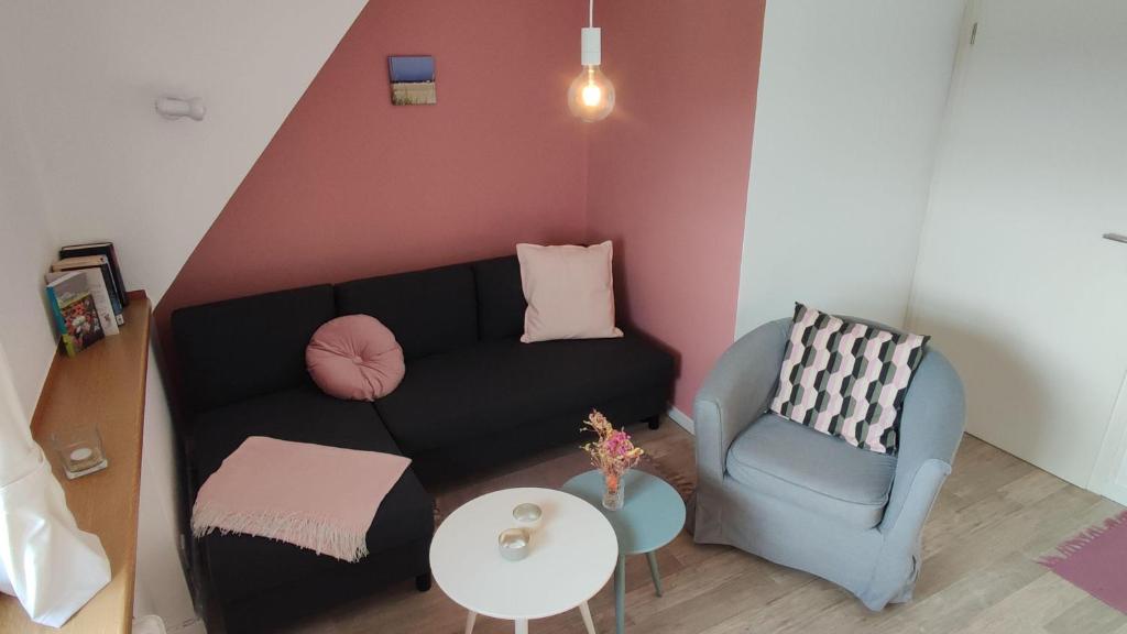 a living room with a black couch and a chair at Landhaus-Sutje-Deichblick in Böhl