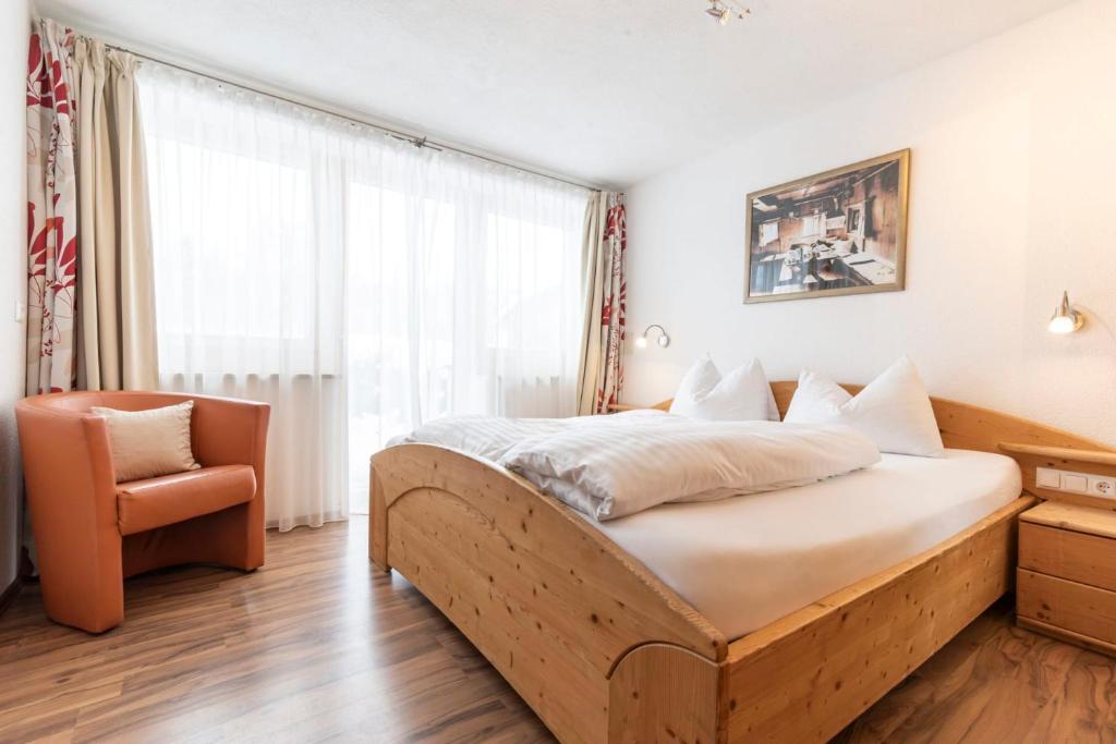 a bedroom with a large bed and a chair at Edelweiss Ladis im Sommer inklusive Super Sommer Card in Ladis