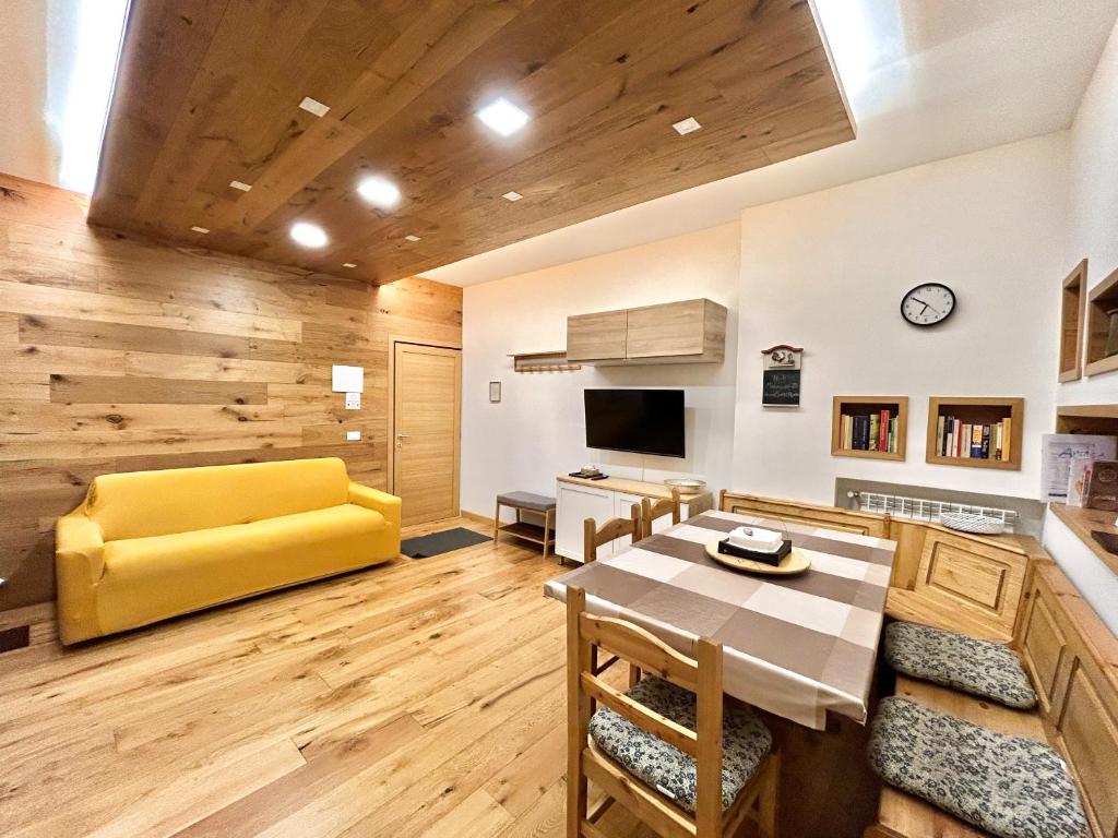 ein Wohnzimmer mit einem gelben Sofa und einem Tisch in der Unterkunft Moderno TRILOCALE vicino alle piste in San Pietro