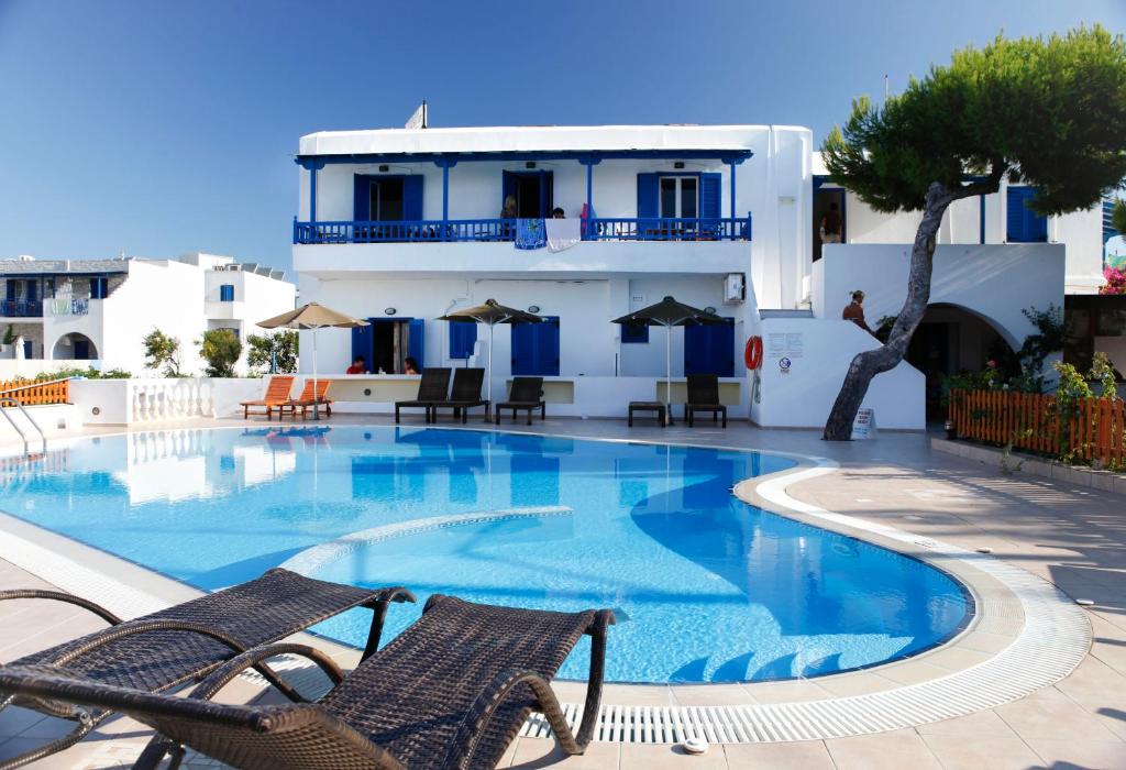 a swimming pool with two chairs and a building at Anna Studios in Agios Prokopios