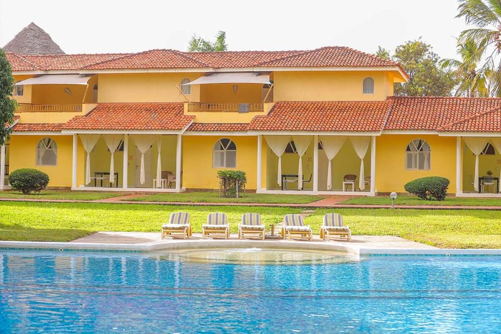 a house with three chairs and a swimming pool at Mwembe Resort - The Village in Malindi