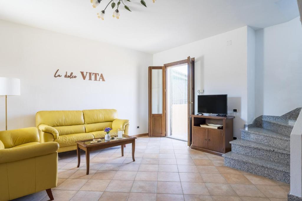 uma sala de estar com um sofá amarelo e uma televisão em La dolce vita Barisardo em Bari Sardo
