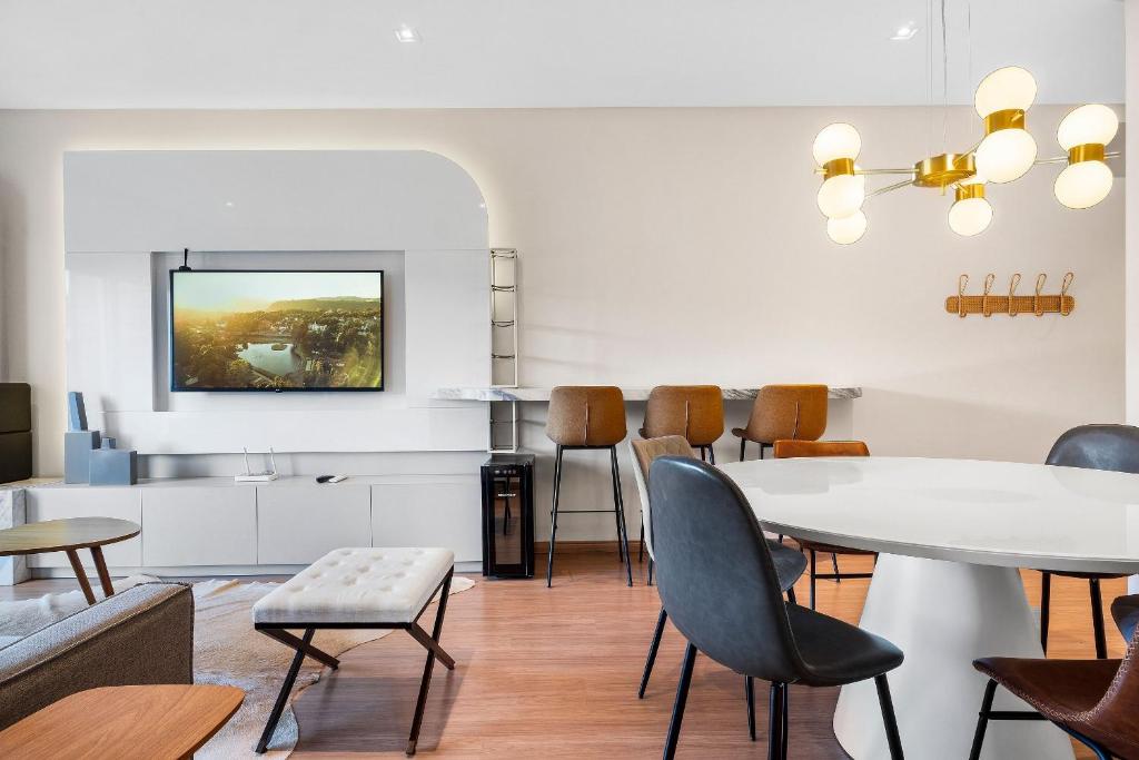 - un salon avec une table et des chaises blanches dans l'établissement Apartamento Essence 2 Suítes by Achei Gramado, à Gramado