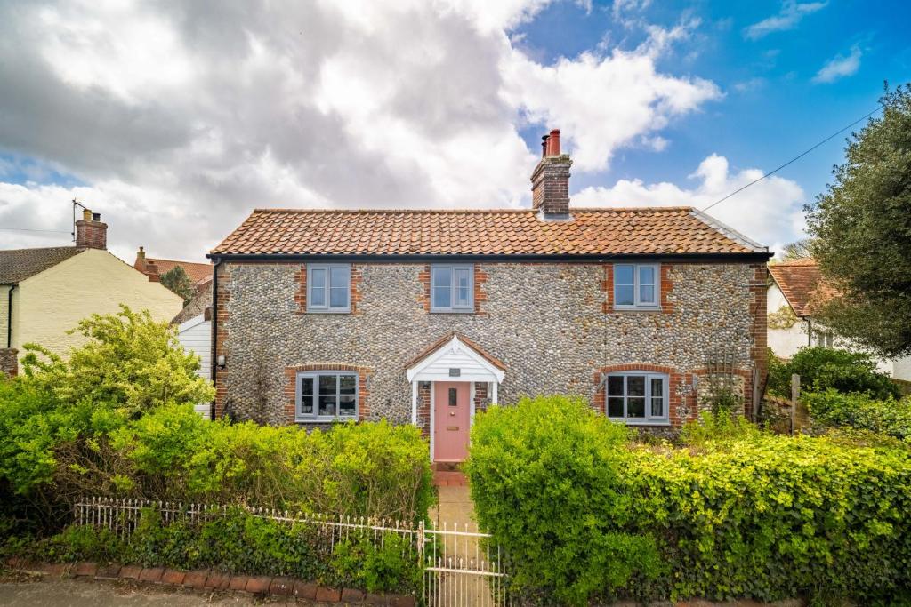 a brick house with a pink door at Ruthie Cottage by Big Skies Cottages in Bacton
