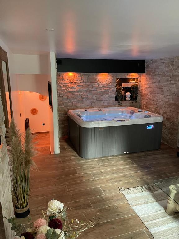 bañera grande en una habitación con pared de ladrillo en Château de la sagesse SPA, en Rouen