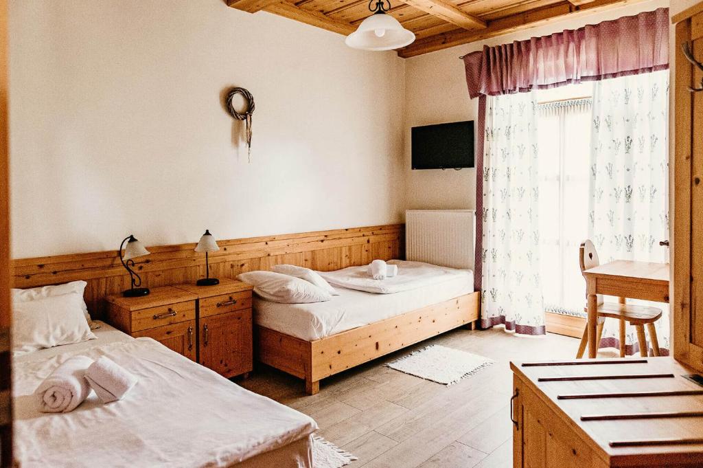 - une chambre avec 2 lits, un bureau et une fenêtre dans l'établissement Kakukk Vendéglő Panzió, à Bánd