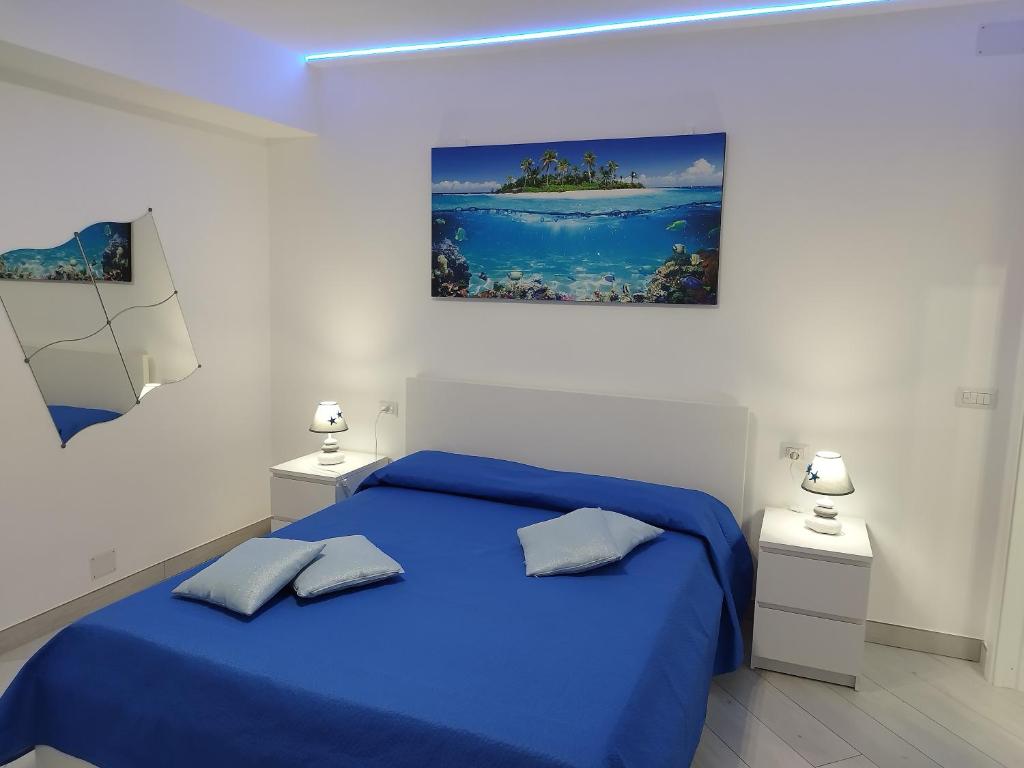 a white bedroom with a blue bed and two lamps at SoleMare Rooms "Acquamarina" in Procida