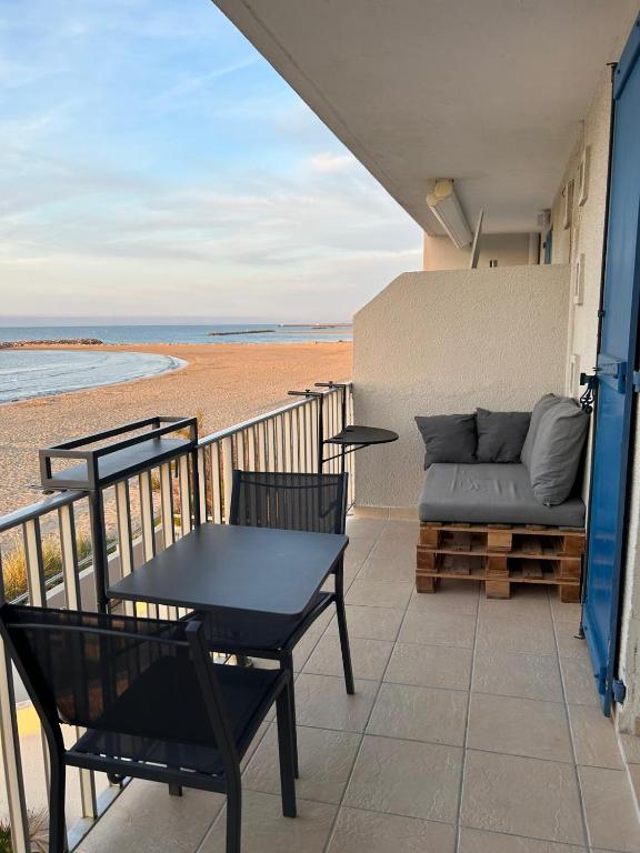 d'un balcon avec une table, des chaises et un canapé. dans l'établissement Carnon Plage, 1ère ligne, balcon sur la mer, à Carnon-Plage