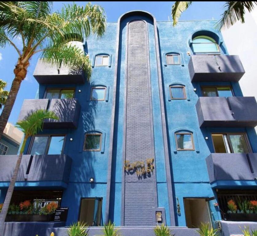 a blue building with palm trees in front of it at Cloud II Los Angeles at Beverly Hills in Los Angeles
