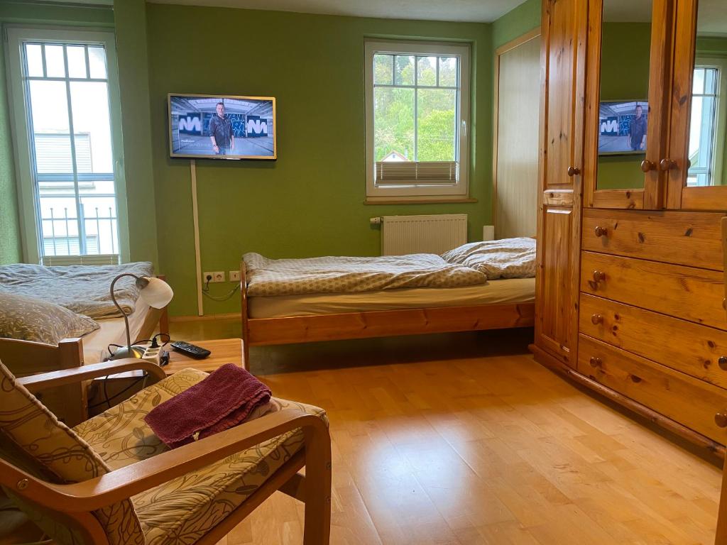 a bedroom with two beds and a tv on the wall at Ferienzimmer Oelhaf Zimmer in Grün Self Check-In mit Key-Tresore in Wilhelmsdorf