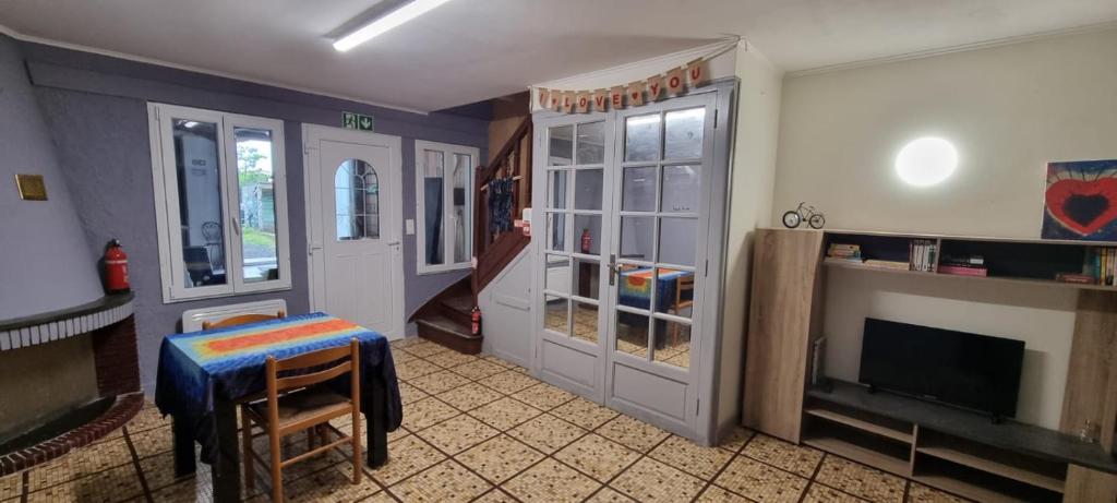 ein Wohnzimmer mit einer Tür, einem Tisch und einem TV in der Unterkunft Maison D'AileFine in Tartas