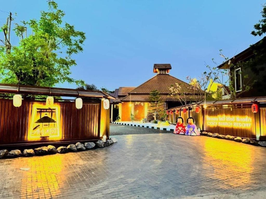 two children sitting on a street in front of a building at COZY SHIROI RESORT in Nang Rong