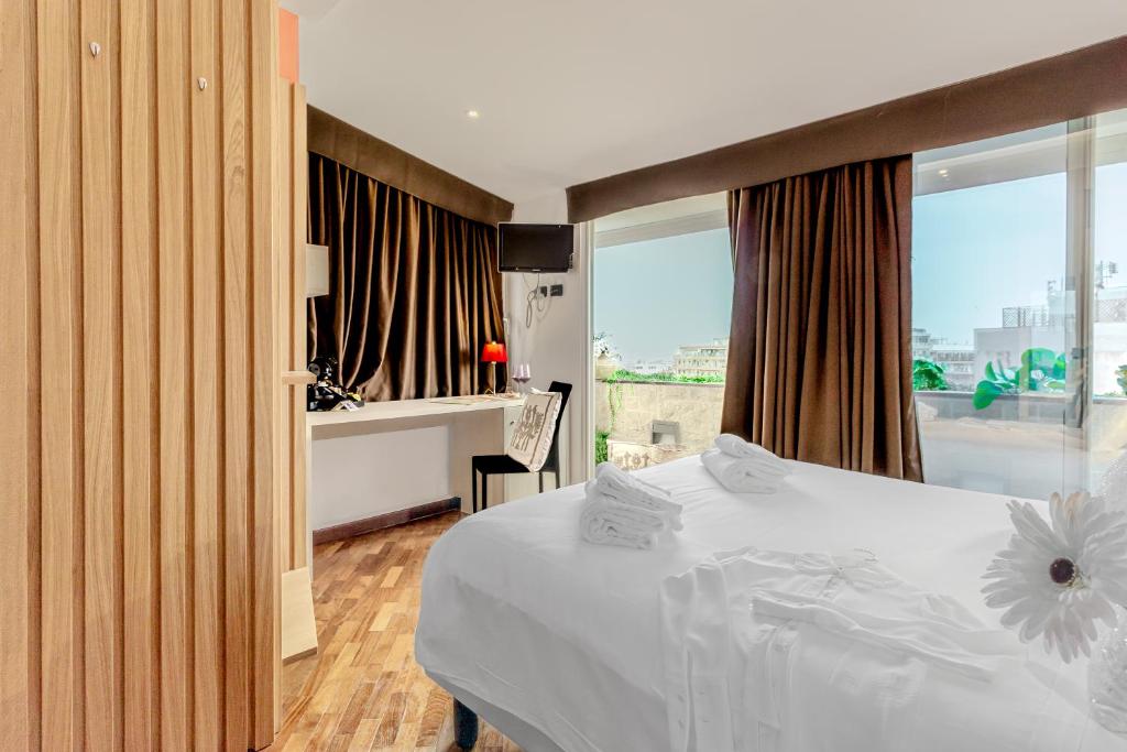 a bedroom with a white bed and a desk and window at Il Panoramico Rooms in Cagliari