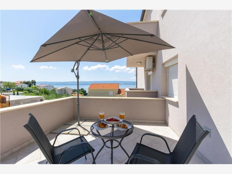 a patio with a table and two chairs and an umbrella at Apartmani Livajić in Duće