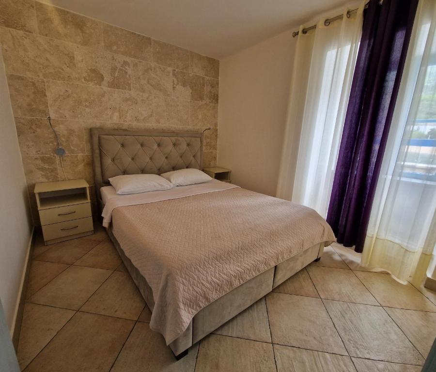 a bedroom with a bed and a stone wall at Kazanegra Exclusive Apartments in Sveti Stefan
