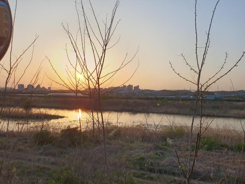 un tramonto su un fiume con una città sullo sfondo di Keumho river house 