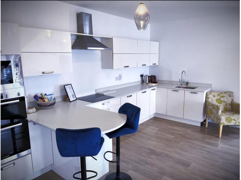 a white kitchen with white cabinets and blue chairs at The Gate House, Kilmullen in Portarlington