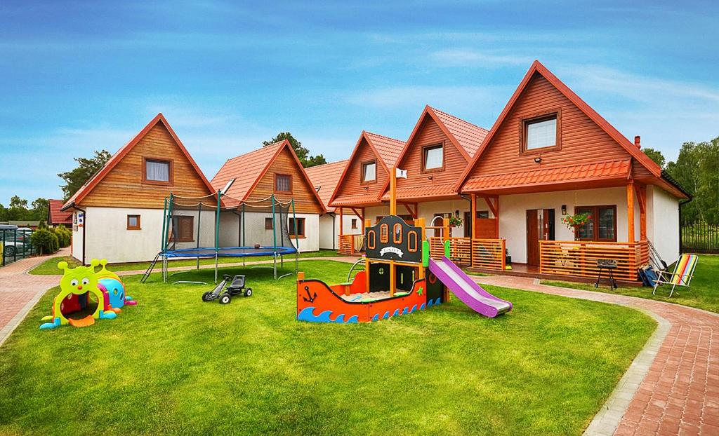 a house with a playground in the front yard at Domki SUNSET Bałtycka in Dąbki