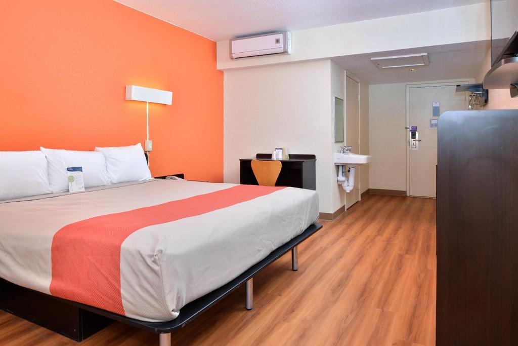 een slaapkamer met een groot bed met een oranje muur bij Days Inn by Wyndham Brawley in Brawley