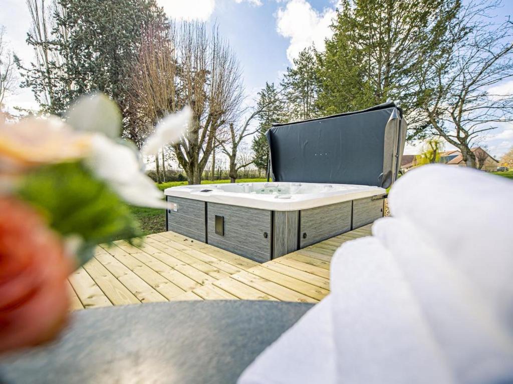 una vasca idromassaggio su una terrazza in legno di Gîte de charme avec spa, terrasse et grand jardin, au cœur des vignobles entre Moulins et Vichy - FR-1-489-507 a Saulcet